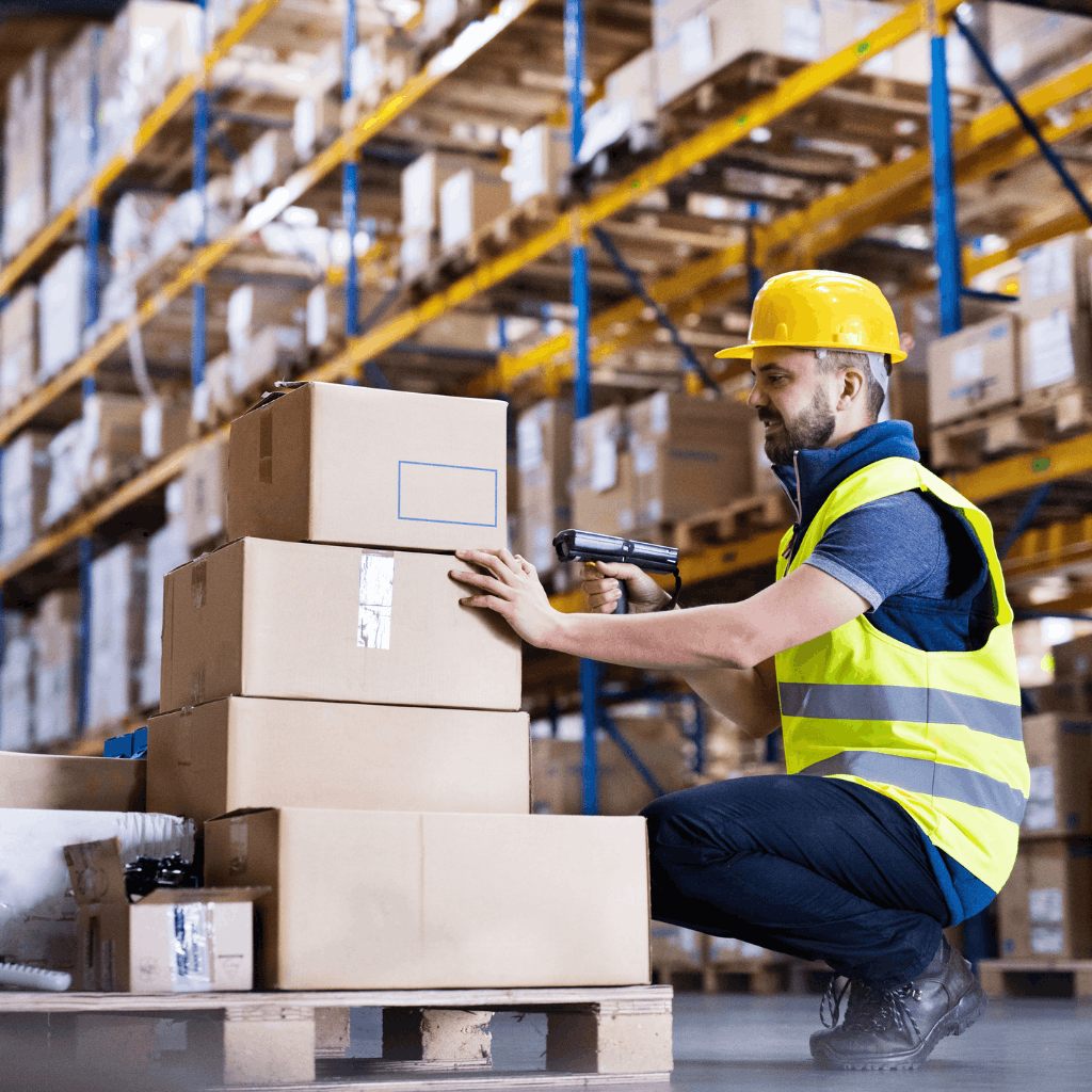 Worker in a warehouse scanning packages with a barcode scanner.